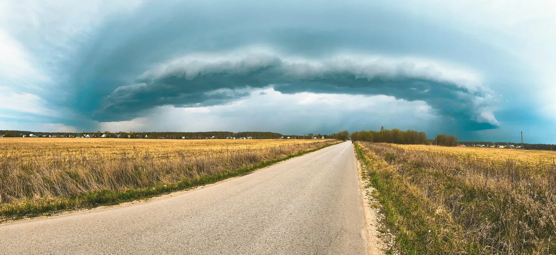 Arcus orageux au-dessus d'une route droite traversant un champ
